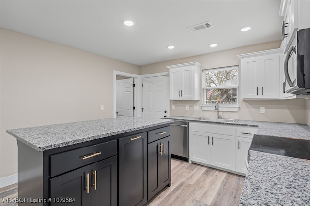 kitchen with white cabinetry, a sink, black microwave, and stainless steel dishwasher