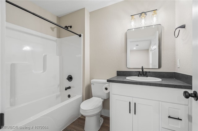 full bath with vanity, toilet, a textured wall, shower / washtub combination, and wood finished floors