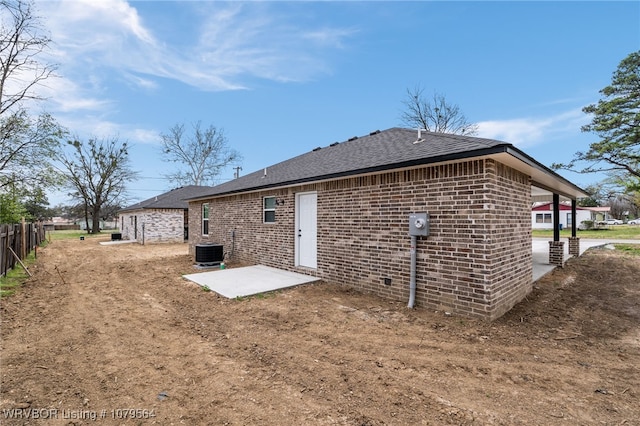 back of house featuring brick siding, central AC unit, fence, and a patio area