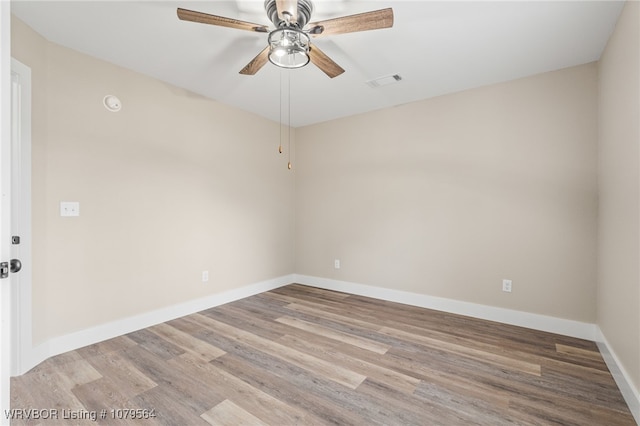 empty room featuring wood finished floors, baseboards, ceiling fan, and visible vents