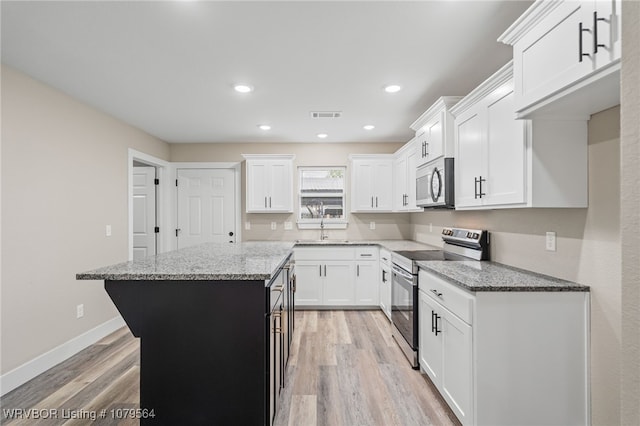 kitchen featuring visible vents, stainless steel appliances, light wood-style floors, and light stone counters