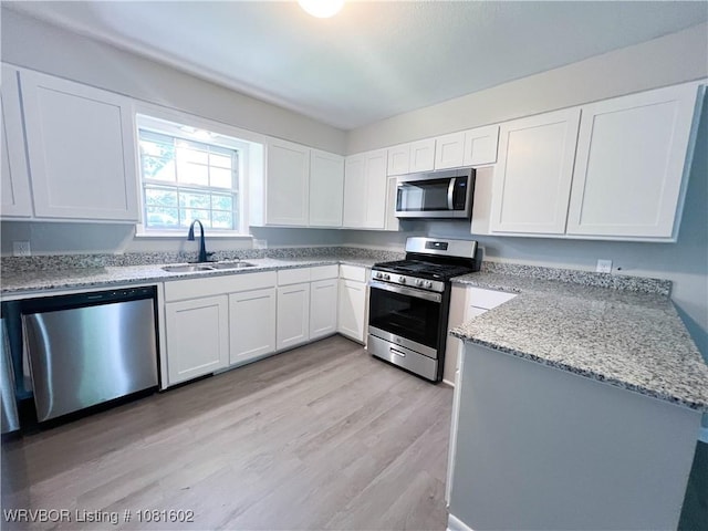 120 W Gary St, Greenwood, AR 72936 - kitchen with stainless steel appliances, a sink, white cabinets, light wood-style floors, and light stone countertops