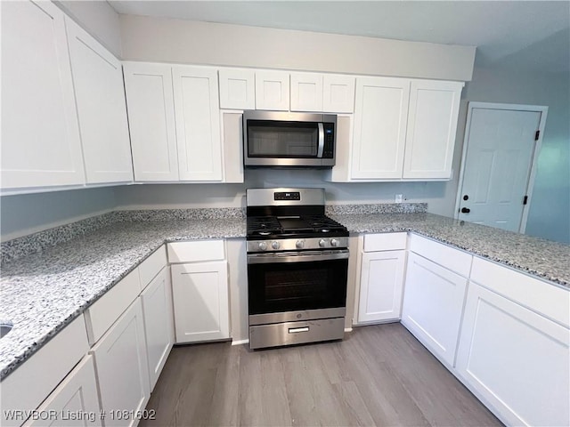 120 W Gary St, Greenwood, AR 72936 - kitchen with appliances with stainless steel finishes, light wood finished floors, white cabinetry, and light stone counters
