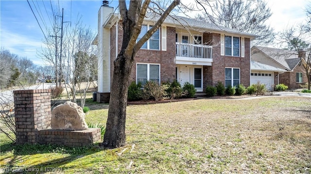 view of front facade featuring brick siding, a front yard, a chimney, a balcony, and an attached garage