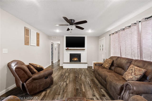 living room with a textured ceiling, ceiling fan, and dark wood-type flooring