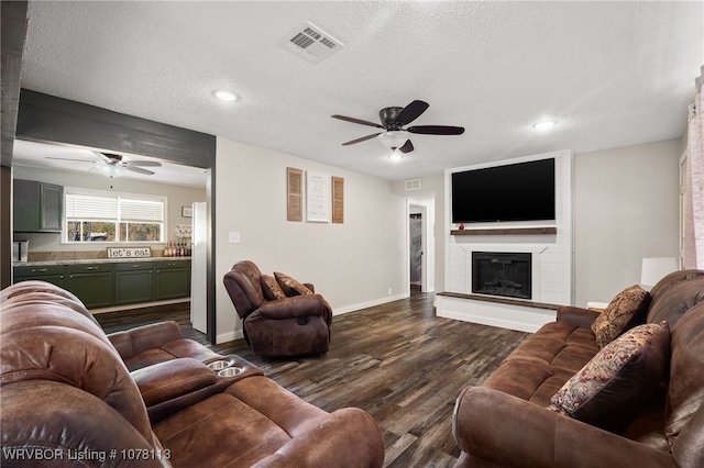 living room with hardwood / wood-style floors, ceiling fan, a fireplace, and a textured ceiling