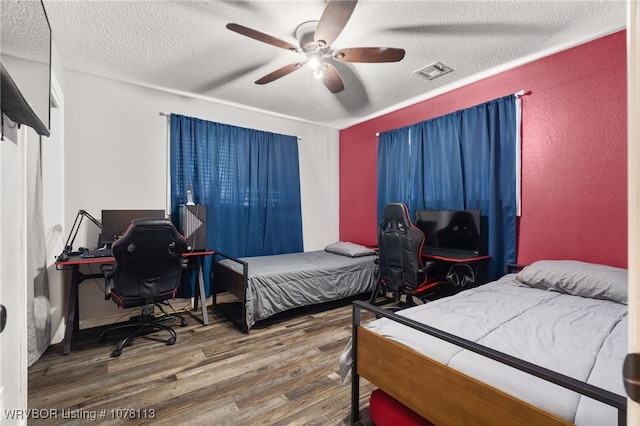 bedroom with hardwood / wood-style floors, ceiling fan, and a textured ceiling