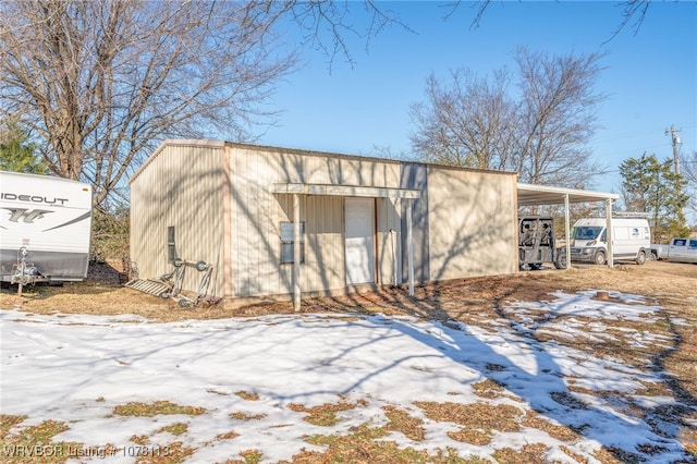 snow covered structure with a carport