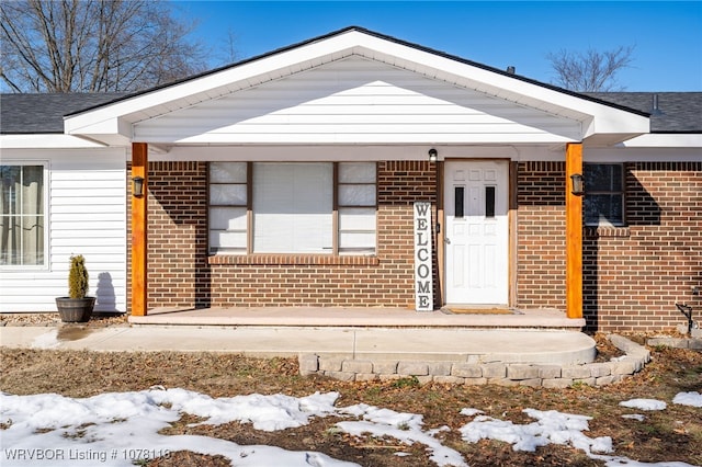 snow covered property entrance with covered porch