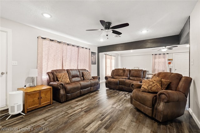 living room featuring ceiling fan, dark hardwood / wood-style flooring, and a textured ceiling