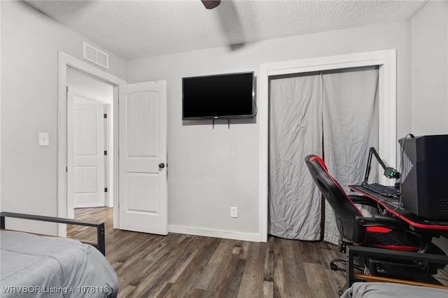 bedroom with a textured ceiling, dark hardwood / wood-style floors, and ceiling fan