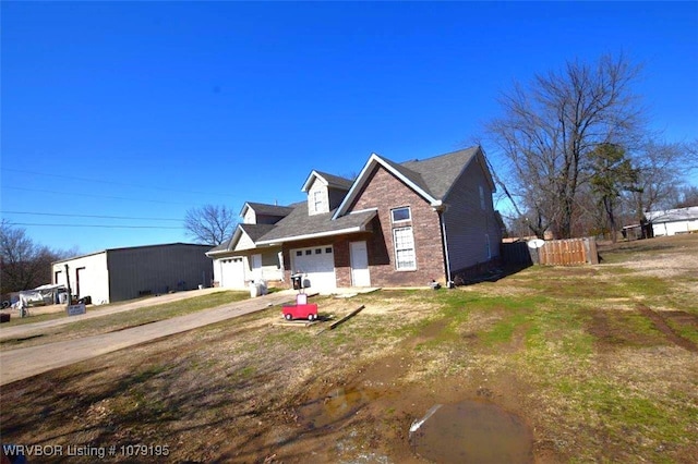 view of front facade with a garage, brick siding, and fence