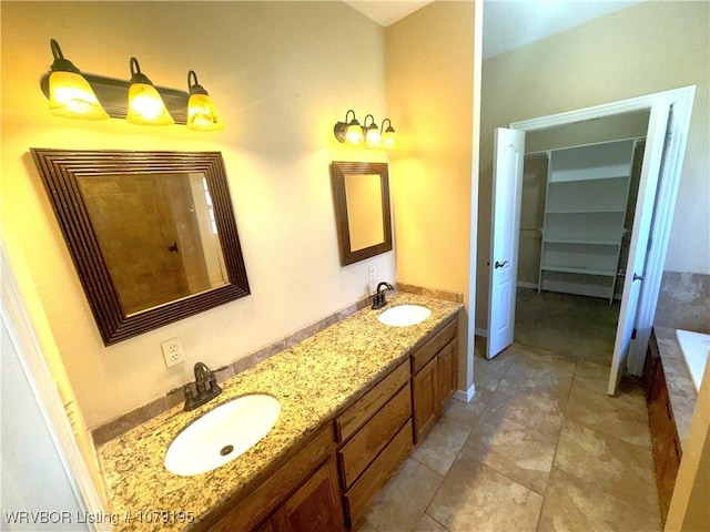 full bathroom featuring double vanity, a relaxing tiled tub, a spacious closet, and a sink