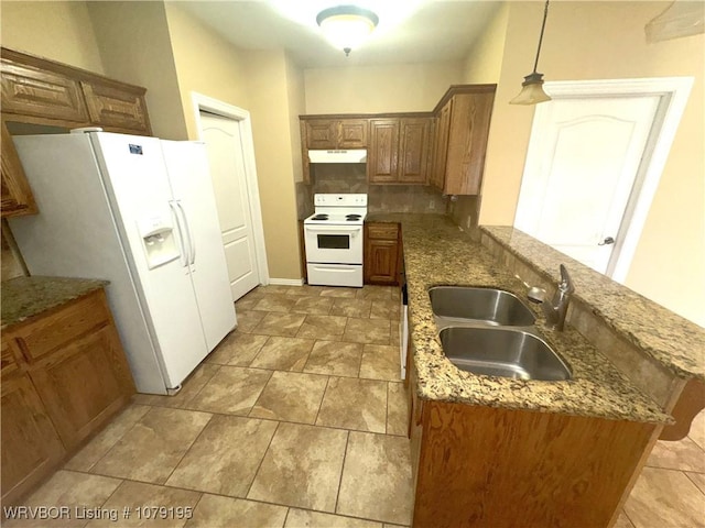 kitchen with under cabinet range hood, white appliances, a sink, brown cabinetry, and pendant lighting