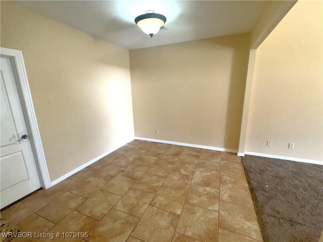 spare room with baseboards and light tile patterned floors