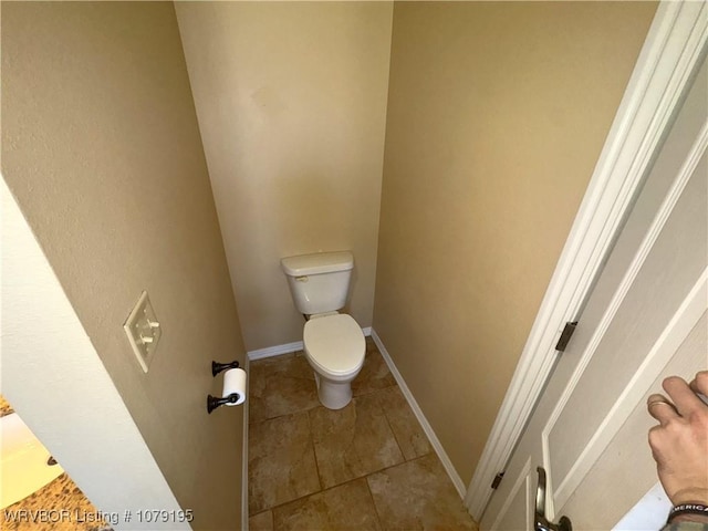 bathroom with toilet, baseboards, and tile patterned floors