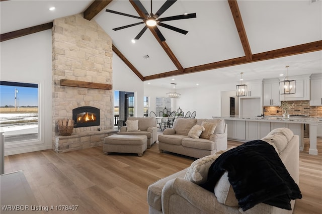 living room with high vaulted ceiling, ceiling fan, a fireplace, and light hardwood / wood-style flooring