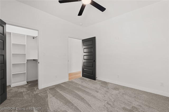 unfurnished bedroom with ceiling fan, a spacious closet, a closet, and carpet