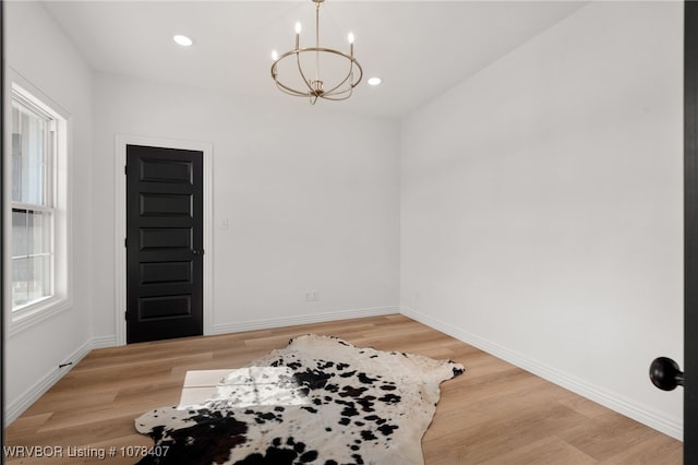 empty room featuring a chandelier and light wood-type flooring