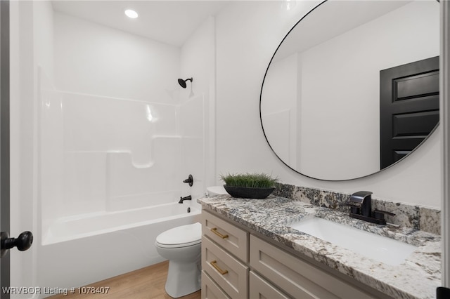 full bathroom featuring hardwood / wood-style floors, toilet, vanity, and shower / washtub combination