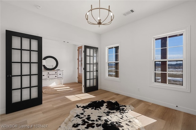 interior space with french doors, a chandelier, and light hardwood / wood-style floors