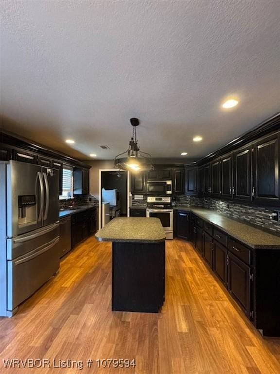 kitchen with stove, stainless steel microwave, light wood-style floors, and fridge with ice dispenser