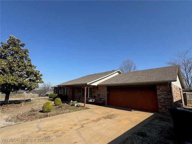 ranch-style house featuring brick siding, an attached garage, driveway, and fence