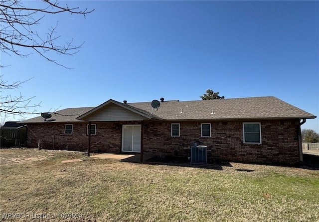 back of property with a lawn, central AC unit, and brick siding