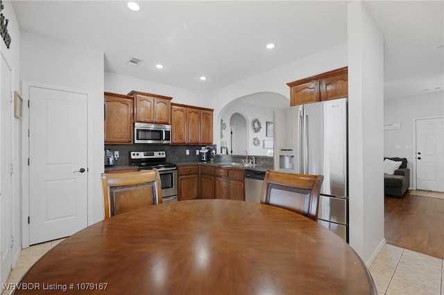 kitchen with arched walkways, dark countertops, visible vents, appliances with stainless steel finishes, and a sink