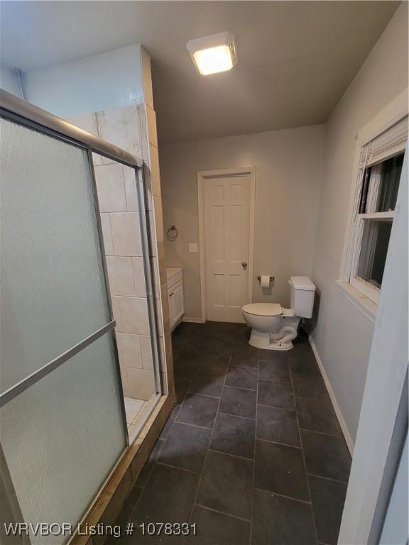 bathroom with vanity, toilet, and a shower with door