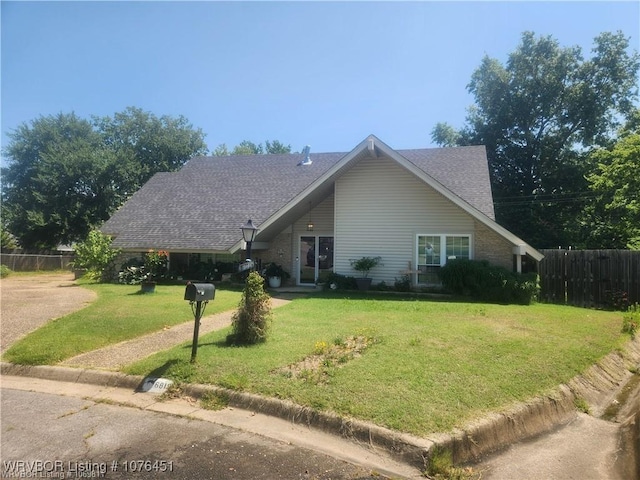 view of front facade featuring a shingled roof, a front yard, and fence