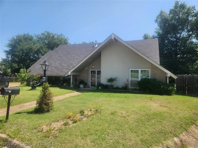 view of front of property featuring roof with shingles, fence, and a front lawn