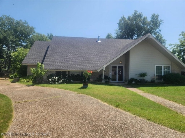 rear view of property with a shingled roof, french doors, and a lawn