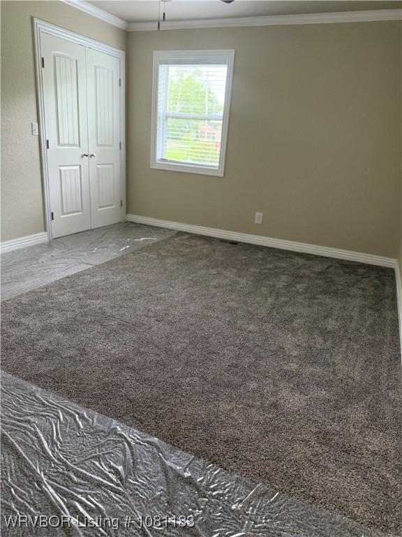 1304 S Elm St, Paris, AR 72855 - unfurnished bedroom with crown molding, baseboards, a closet, and carpet