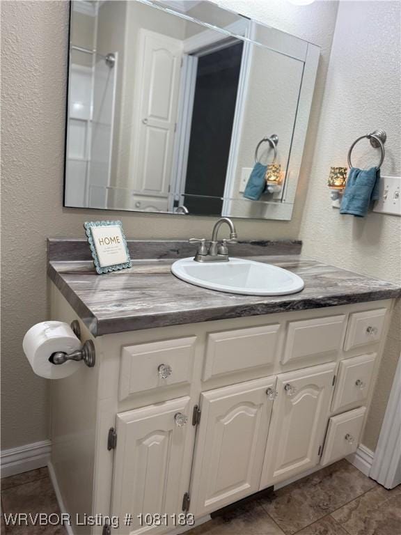 1304 S Elm St, Paris, AR 72855 - bathroom with vanity, a textured wall, baseboards, and tile patterned floors