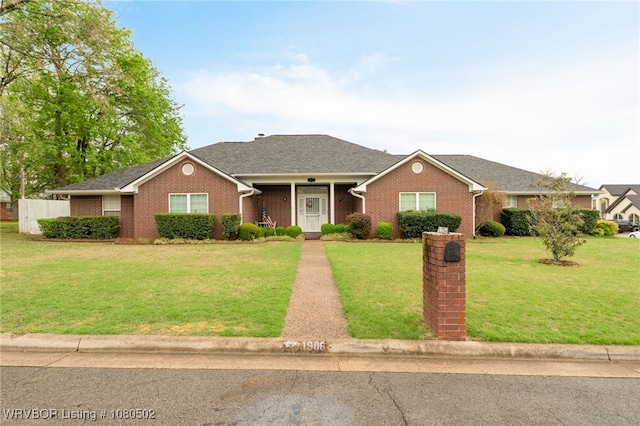 view of front of property with a front lawn, a shingled roof, and brick siding