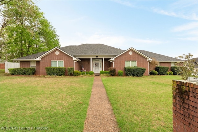 ranch-style home with a front yard, roof with shingles, and brick siding