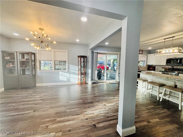 living room with dark hardwood / wood-style flooring, a textured ceiling, and a chandelier