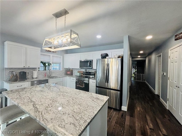 kitchen featuring white cabinets, a center island, stainless steel appliances, and hanging light fixtures