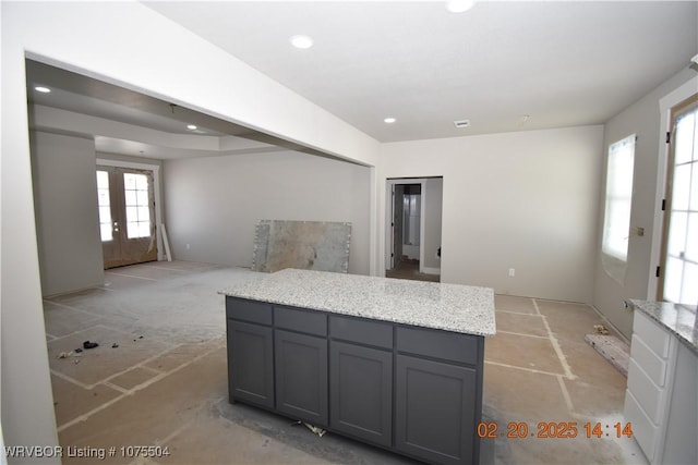 kitchen with gray cabinetry, a kitchen island, light stone counters, french doors, and recessed lighting