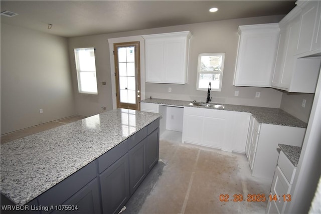 kitchen featuring a center island, recessed lighting, visible vents, white cabinets, and a sink