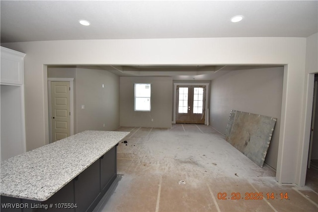 interior space with recessed lighting, dark cabinets, open floor plan, french doors, and a center island