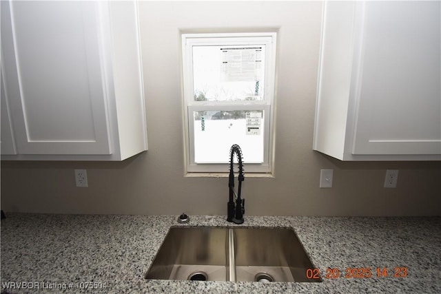 details with light stone counters, white cabinetry, and a sink