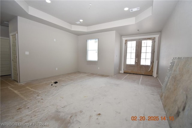 empty room featuring french doors, a raised ceiling, and visible vents