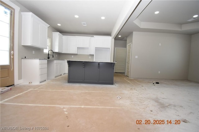 kitchen featuring recessed lighting, a sink, a kitchen island, white cabinetry, and light countertops