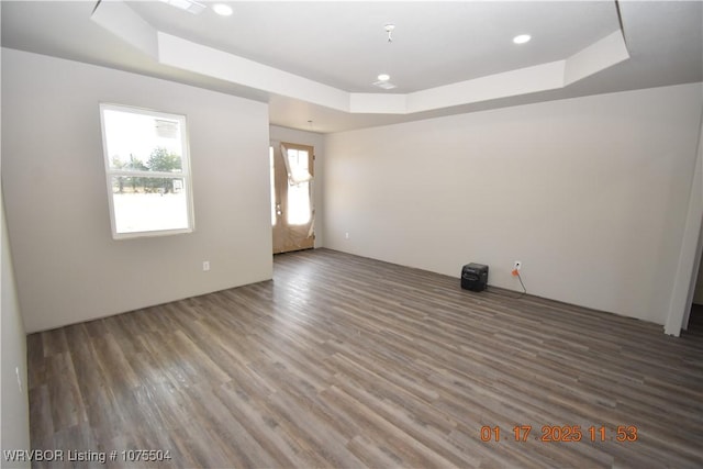 spare room with a tray ceiling, dark wood finished floors, and recessed lighting