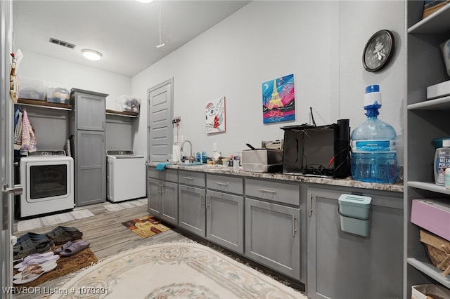 kitchen featuring visible vents, gray cabinets, open shelves, a sink, and light wood-style floors