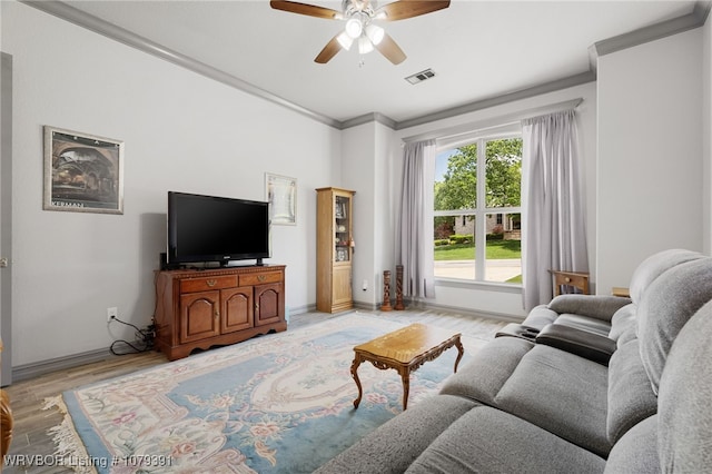 living area featuring visible vents, crown molding, baseboards, light wood-type flooring, and a ceiling fan