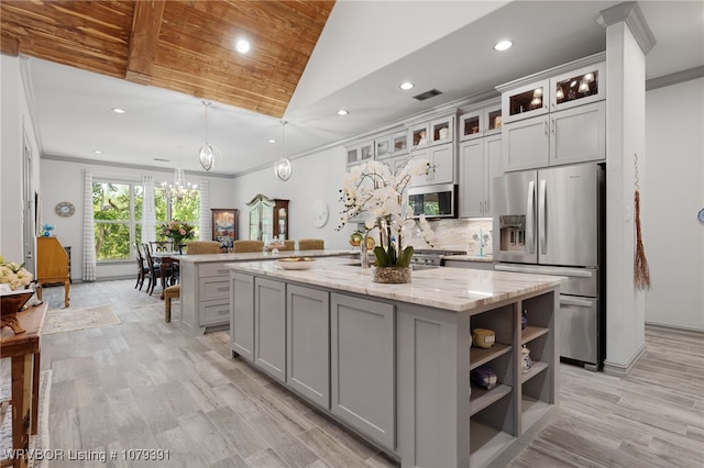 kitchen featuring ornamental molding, gray cabinetry, a center island with sink, and stainless steel appliances