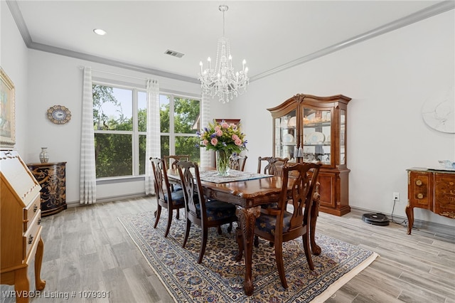 dining area featuring visible vents, light wood-style floors, an inviting chandelier, and ornamental molding